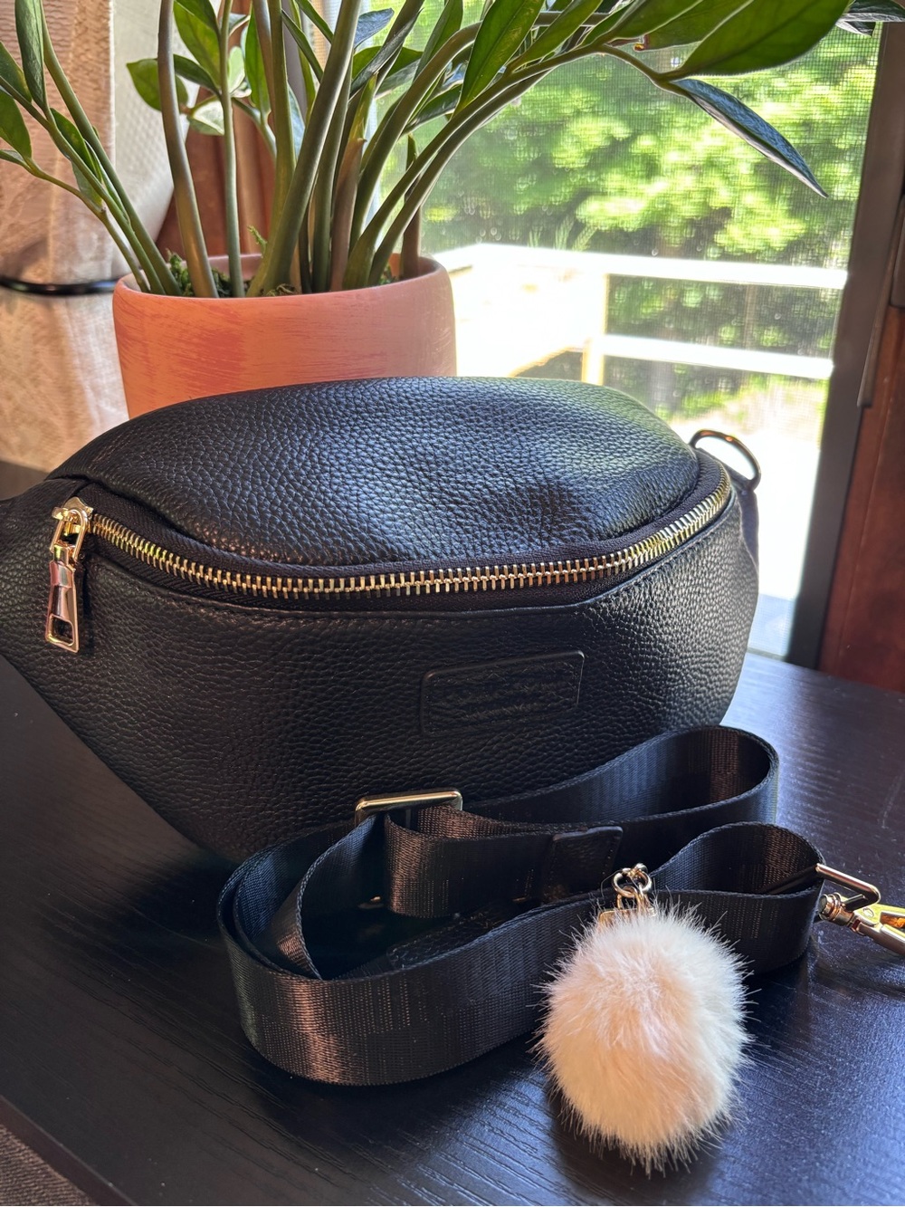 Black Pebbled Leather Crossbody Belt Bag with Pom Pom Accent